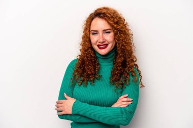 Beyaz arka planda kendini güvende hisseden, kararlılıkla kollarını kavuşturan beyaz tenli genç bir beyaz kadın..