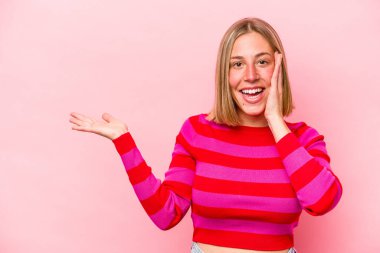 Pembe arka planda izole edilmiş genç beyaz kadın avuç içinde fotokopi alanı tutuyor, el üstünde tutuyor. Şaşırmış ve mutlu..