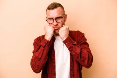 Beyazlı genç bir adam bej arka planda izole edilmiş. Yumruk atıyor, sinirleniyor, tartışıyor, boks yapıyor..