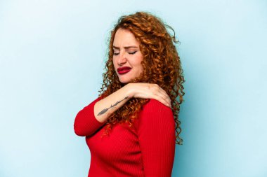 Genç, beyaz, mavi arka planda izole edilmiş, omuz ağrısı olan bir kadın..