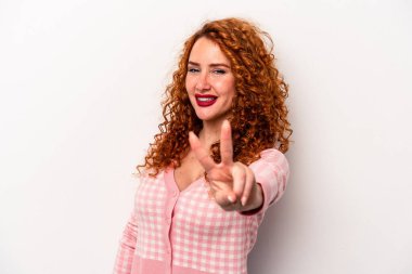 Beyaz arka planda izole edilmiş genç, beyaz, beyaz bir kadın neşeli ve kaygısız parmaklarıyla barış sembolü gösteriyor..