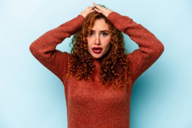 Genç, beyaz, mavi arka planda izole edilmiş kadın şaşırmış ve şok olmuş..
