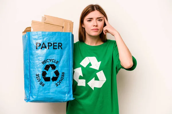 白い背景に隔離された紙をリサイクルするためにリサイクルバッグを持っている若い女性は 額で失望のジェスチャーを示しています — ストック写真
