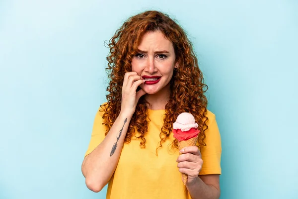 Joven Pelirroja Sosteniendo Helado Aislado Sobre Fondo Azul Mordiendo Las —  Fotos de Stock