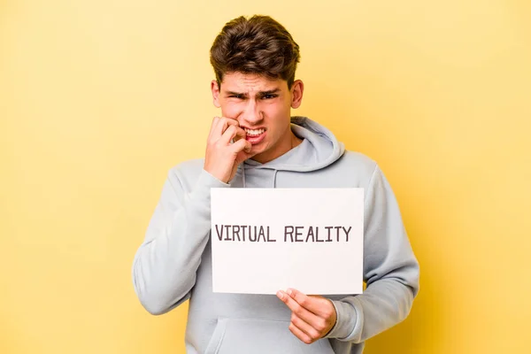 Jovem Caucasiano Segurando Cartaz Virtual Isolado Fundo Amarelo Mordendo Unhas — Fotografia de Stock