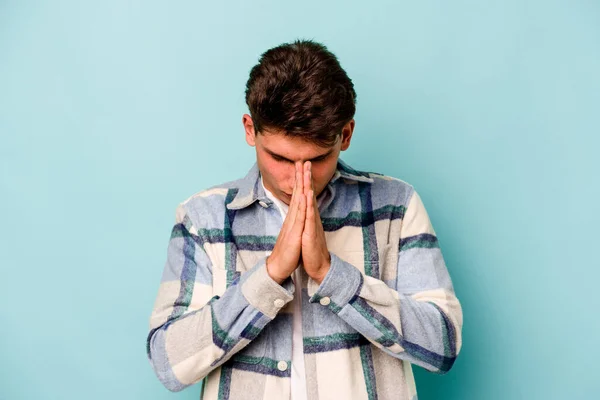 Joven Hombre Caucásico Aislado Sobre Fondo Azul Rezando Mostrando Devoción —  Fotos de Stock