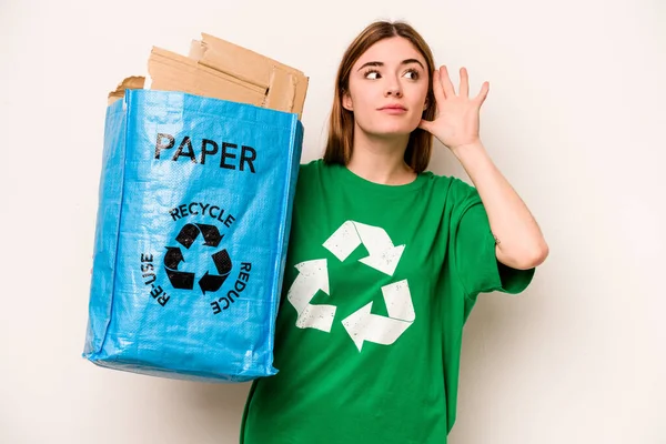 白い背景に隔離された紙をリサイクルするためにリサイクルバッグを持っている若い女性はゴシップを聞こうとしています — ストック写真
