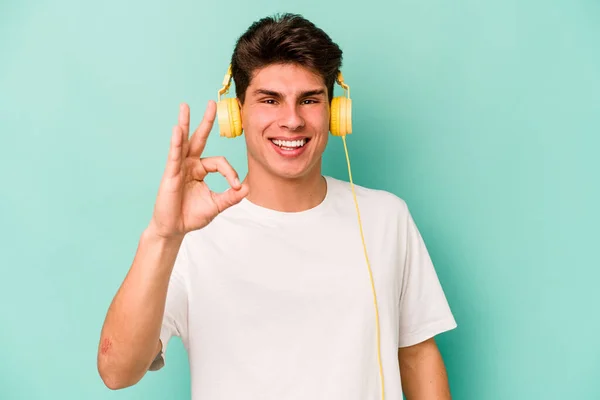 Jovem Caucasiano Homem Ouvindo Música Isolada Fundo Azul Alegre Confiante — Fotografia de Stock
