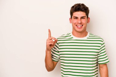 Beyaz arka planda izole edilmiş beyaz tenli genç bir adam bir numarayı parmağıyla gösteriyor..