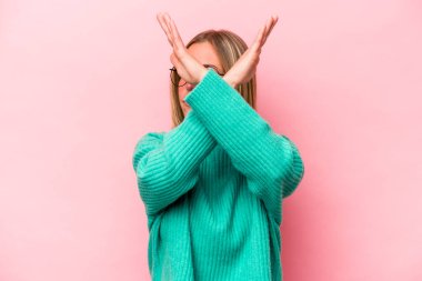 Pembe arka planda izole edilmiş genç beyaz kadın iki kolu çapraz tutuyor, inkar kavramı.