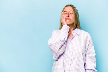 Mavi arka planda izole edilmiş, üzgün ve dalgın hisseden, kopyalama alanına bakan beyaz bir kadın..