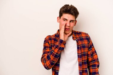 Beyaz arka planda izole edilmiş genç beyaz bir adam gizli bir sıcak fren haberi veriyor ve yana bakıyor.