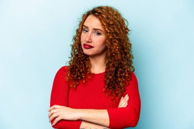 Genç beyaz kadın, mavi arka planda izole edilmiş şüpheli, belirsiz, seni muayene ediyor..