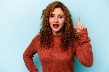 Genç, beyaz, mavi arka planda izole edilmiş bir kadın. Bir fikri, ilham verici bir fikri var..