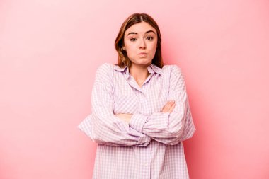 Pembe arka planda izole edilmiş genç beyaz kadın yanakları patlatıyor, yorgun bir ifade takınıyor. Yüz ifadesi kavramı.