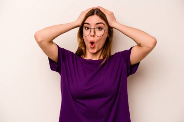 Beyaz arka planda izole edilmiş genç beyaz kadın şaşırmış ve şok olmuş..