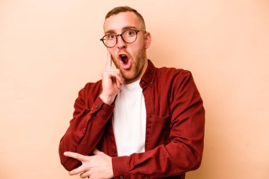 Beyazlı genç bir adam bej arka planda izole edilmiş. Harika bir fikri var, yaratıcılık kavramı..