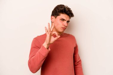 Beyaz arka planda izole edilmiş genç beyaz bir adam bir göz kırptı ve elleriyle iyi bir jest yaptı..