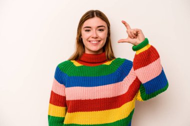 Beyaz arka planda izole edilmiş genç beyaz bir kadın. Elinde parmakları olan, gülümseyen ve kendinden emin bir şey tutuyor..