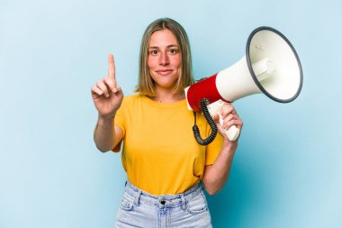 Elinde megafon tutan beyaz bir kadın mavi arka planda bir numarayı parmağıyla gösteriyor..