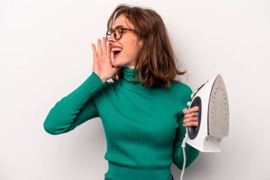 Beyaz arka planda demir tutan genç beyaz kadın bağırıyor ve avuç içini açık tutuyor..