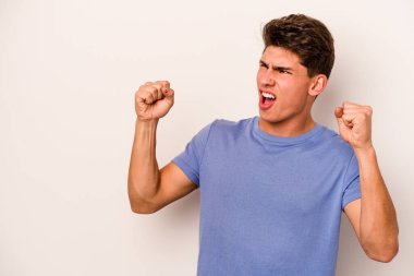 Beyaz arka planda izole edilmiş genç beyaz bir adam zaferden sonra yumruğunu kaldırıyor, kazanan konsept.