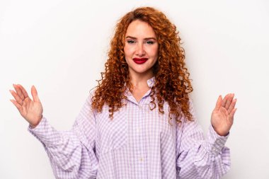 Beyaz arka planda izole edilmiş beyaz tenli genç bir kadın. Elinde parmakları olan, gülümseyen ve kendinden emin bir şey tutuyor..