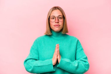 Pembe arka planda izole edilmiş genç beyaz kadın dua ediyor, bağlılık gösteriyor, dindar biri ilahi ilham arıyor..