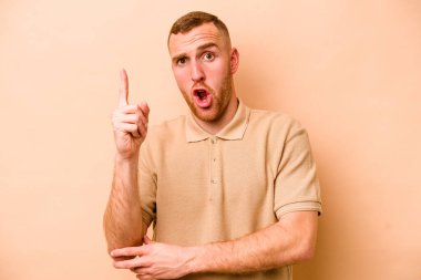 Beyazlı genç bir adam bej arka planda izole edilmiş. Harika bir fikri var, yaratıcılık kavramı..