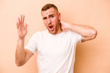 Beyazlı genç adam bej arka planda izole edilmiş öfkeyle bağırıyor..
