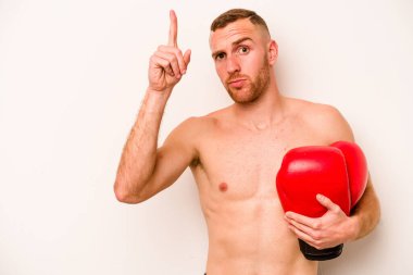 Beyaz arka planda boks yapan beyaz tenli genç bir adam bir numarayı parmağıyla gösteriyor..