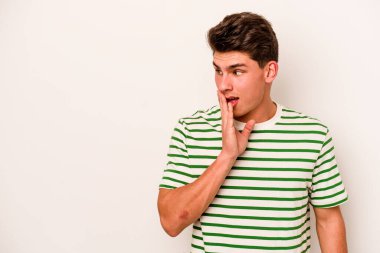 Beyaz arka planda izole edilmiş genç beyaz bir adam gizli bir sıcak fren haberi veriyor ve yana bakıyor.