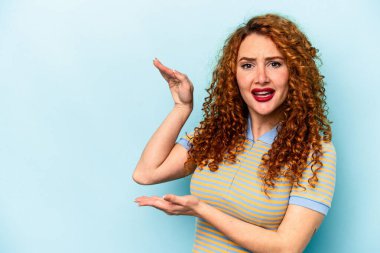 Mavi arka planda izole edilmiş genç beyaz kadın elleri arasında bir kopya alanı tutarken şok ve hayrete düştü..