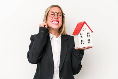 Beyaz arka planda izole edilmiş, elleri kulaklarında oyuncak evi tutan beyaz bir kadın..