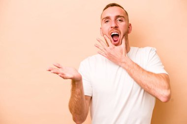 Beyazların arka planında izole edilmiş genç beyaz bir adam bir avuç içinde fotokopi alanı tutuyor, el üstünde tutuyor. Şaşırmış ve mutlu..