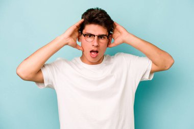 Kafkasyalı genç adam mavi arka planda izole edildi. Şaşırdı ve şok oldu..