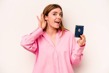 Beyaz arka planda izole edilmiş genç, gayri resmi beyaz kadın bir dedikoduyu dinlemeye çalışıyor..