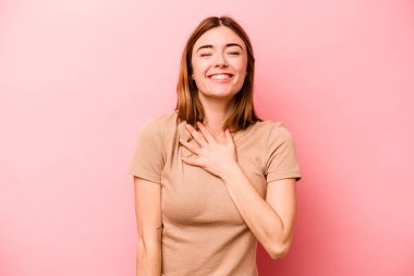 Pembe arka planda soyutlanmış beyaz bir kadın yüksek sesle gülüyor ve elini göğsüne koyuyor..