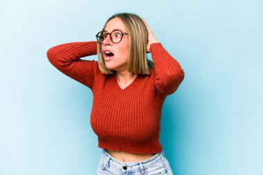 Mavi arka planda izole edilmiş genç beyaz kadın çığlık atıyor, çok heyecanlı, tutkulu, bir şeyden memnun..
