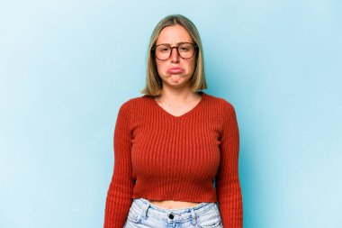 Genç beyaz kadın mavi arka planda izole edilmiş üzgün, ciddi yüzlü, mutsuz ve hoşnutsuz..