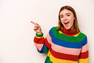 Beyaz arka planda izole edilmiş genç beyaz kadın işaret parmağıyla işaret ederek gülümsüyor..