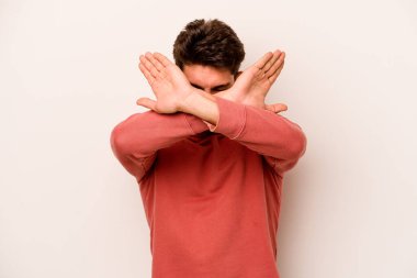 Beyaz arka planda izole genç beyaz adam iki kolu çapraz tutuyor, inkar kavramı.