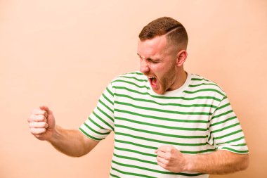 Genç beyaz adam bej arka planda izole edilmiş dans ediyor ve eğleniyor..