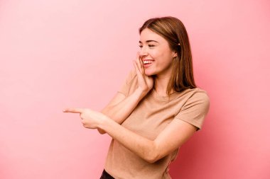 Pembe arka planda izole edilmiş genç beyaz bir kadın bir dedikodu söylüyor, bir haber sunuyor..