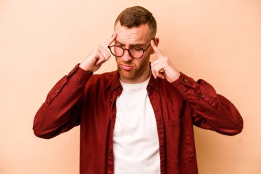 Kafkasyalı genç bir adam bej arka planda izole edilmiş, başı ağrıyor, yüzüne dokunuyor..