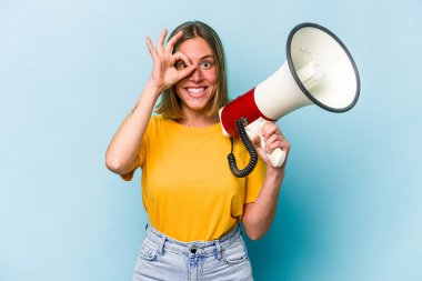 Mavi arka planda izole edilmiş bir megafon tutan beyaz bir kadın heyecanlı..