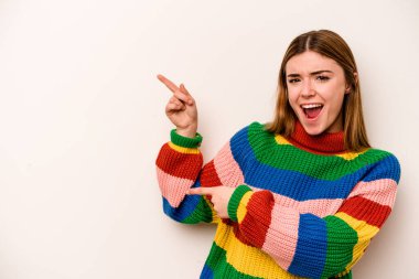 Beyaz arka planda izole edilmiş beyaz tenli genç bir kadın işaret parmağıyla işaret ederek heyecanlanıyor..