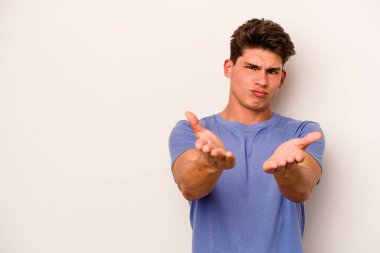 Beyaz arka planda izole edilmiş genç beyaz bir adam dudaklarını katlıyor ve hava öpücüğü vermek için avuç içleri tutuyor..