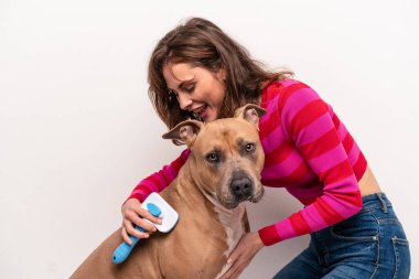 Beyaz arka planda köpeğini tarayan beyaz bir kadın.