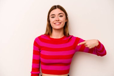 Beyaz arka planda yaşayan beyaz tenli genç bir kadın gömlek fotokopi alanını elle işaret ediyor, gururlu ve kendinden emin